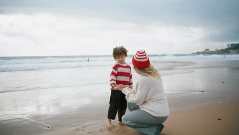Babysitter-teaching-little-boy-at-autumn-seaside.-Beautiful-single-mom-playing