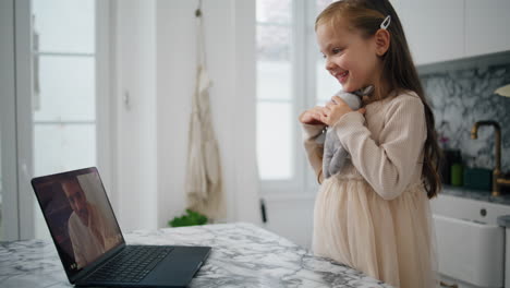 Lovely-child-waving-laptop-at-kitchen-close-up.-Happy-daughter-speaking-remotely