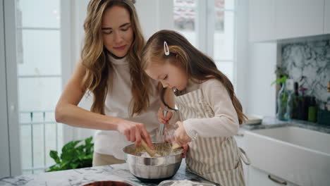 Caring-woman-talking-child-at-kitchen-close-up.-Positive-family-creating-dough