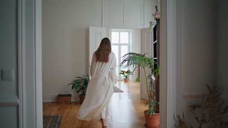 Young-lady-opening-doors-at-morning-interior.-Relaxed-girl-walking-at-cozy-home