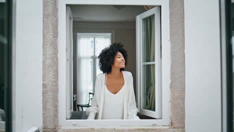 Black-hair-girl-waving-window-morning-house.-Curly-smiling-woman-peeping-outside