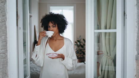 Relaxed-model-drinking-coffee-cup-window-closeup.-Dark-skin-woman-looking-street