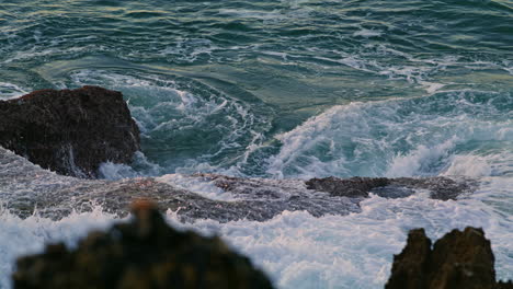 Churning-sea-washing-crag-dusk-environment-closeup.-Swirling-aqua-hitting-shore