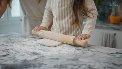 Child-hands-rolling-dough-at-home-closeup.-Unknown-family-cooking-cake-together