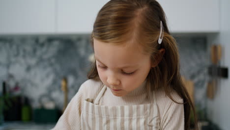 Focused-child-holding-whisk-kitchen-closeup.-Little-girl-preparing-dough-alone