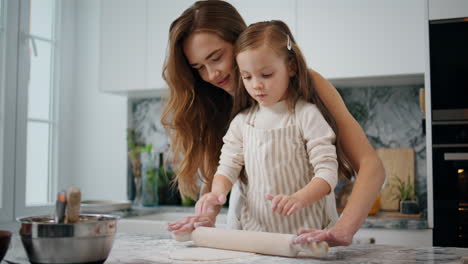 Adorable-mom-daughter-kneading-dough-with-pin-close-up.-Woman-bonding-to-child