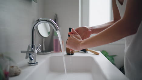 Woman-washing-hands-faucet-at-home-closeup.-Unknown-lady-using-bathroom-sink