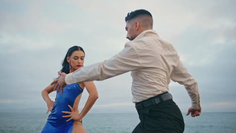 Couple-professionals-dancing-sensually-at-cloudy-sea.-Dancers-performing-latino