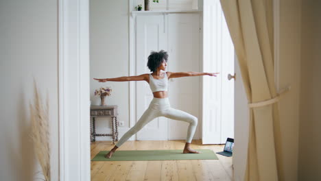 Calm-lady-practicing-yoga-home.-African-girl-stretching-body-at-white-interior