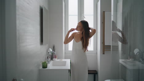 Calm-girl-holding-hairbrush-in-bathroom-alone.-Woman-doing-hair-care-routine