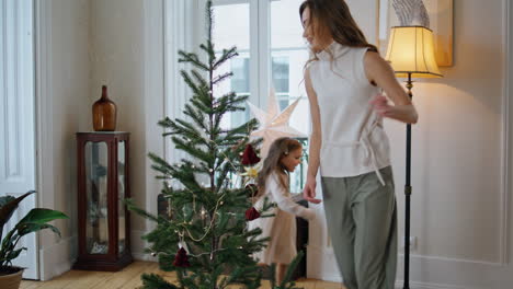 Funny-daughter-catching-mom-at-Christmas-tree-room.-Smiling-woman-running-away