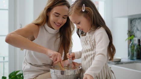 Mom-daughter-whisking-dough-indoors-closeup.-Mother-kid-mixing-flour-together