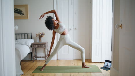 Flexible-woman-stretching-body-in-cozy-place.-Curly-hair-athlete-practice-asana