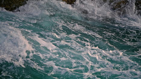 Foamy-waves-splashing-at-crag-nature-close-up.-Salty-sea-water-crashing-by-rocks