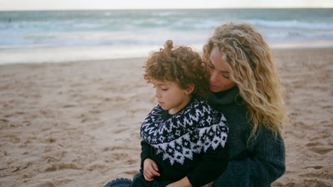 Mother-cover-blanket-kid-on-cold-beach-picnic-closeup.-Unconditional-parent-love