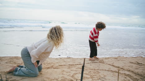 Little-boy-playing-ocean-shore-with-mother.-Family-weekend-on-autumn-beach.