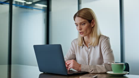 Serious-businesswoman-calling-laptop-at-conference-room.-Focused-woman-talking