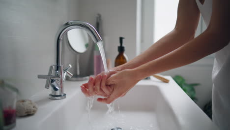 Girl-washing-hands-at-bathroom-sink-closeup.-Woman-rubbing-fingers-under-faucet