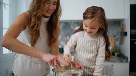 Mother-daughter-hands-creating-dough-home-close-up.-Positive-family-at-kitchen