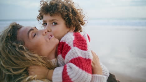 Happy-mother-cuddling-son-at-autumn-ocean-shore-closeup.-Sincere-family-emotions