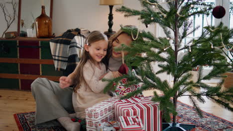 Weihnachten-Familie-Zärtlich-Chatten-In-Der-Nähe-Von-Dekorierten-Baum-Im-Haus.-Mädchen-Wählen-Geschenk