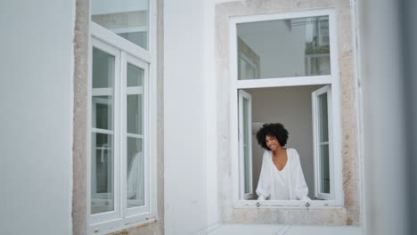 Domestic-girl-peeping-window-morning-indoors.-African-lady-looking-camera-alone