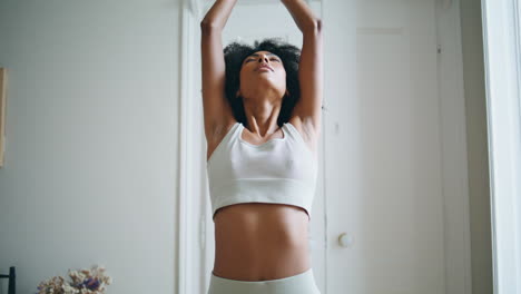 Sport-model-hands-raised-at-morning-training-indoor.-African-woman-namaste-pose