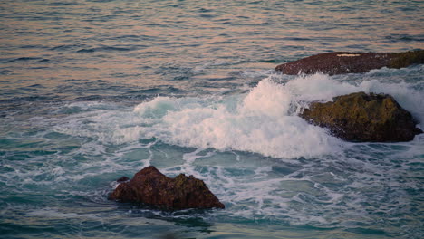 Schaumige-Wellen-Rollen-Auf-Dunklen-Felsen-In-Der-Nähe.-Wirbelndes-Aqua,-Atemberaubende-Meereslandschaft
