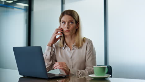 Serious-entrepreneur-talking-mobile-phone-in-office.-Woman-having-cellphone-call