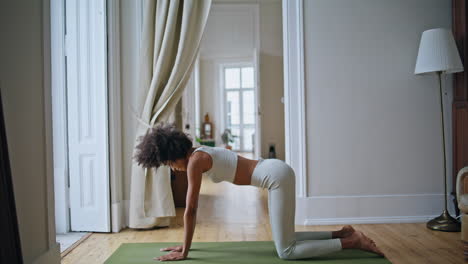 Flexible-girl-cat-cow-pose-practicing-indoors.-Black-skin-woman-bending-body-mat