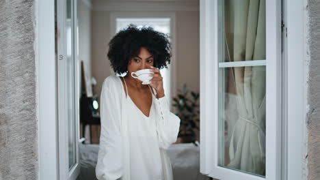 Calm-model-drinking-coffee-window-close-up.-African-girl-enjoying-hot-beverage