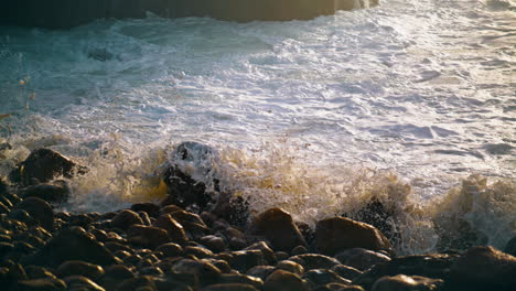 Wellen-Treffen-Im-Morgensonnenlicht-Auf-Strandfelsen.-Nahaufnahme-Von-Schäumendem-Wasser,-Das-Plätschert