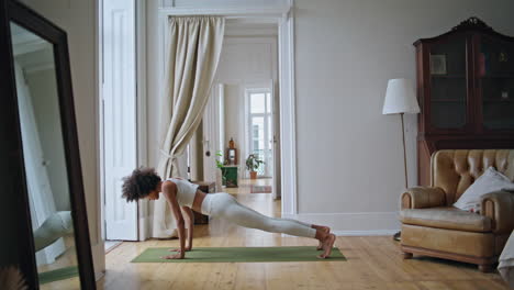 Athletic-lady-yoga-training-at-white-room.-African-girl-doing-back-stretching
