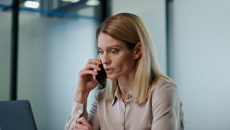 Confident-businesswoman-talking-cellphone-in-office.-Serious-manager-calling