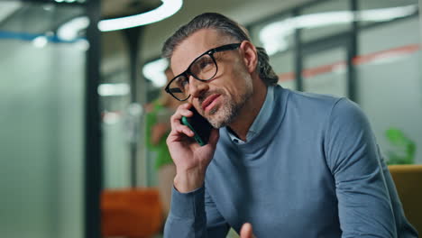 Smiling-director-calling-phone-corporate-office-closeup.-Man-talking-telephone