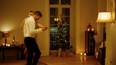 Happy-lovers-sensual-dance-cozy-flat.-Couple-moving-at-Christmas-tree-interior