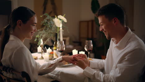 Happy-guy-wearing-engagement-ring-at-evening-room.-Couple-touching-foreheads