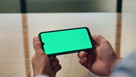 Businessman-hands-watching-chromakey-device-workplace.-Man-holding-mockup-phone