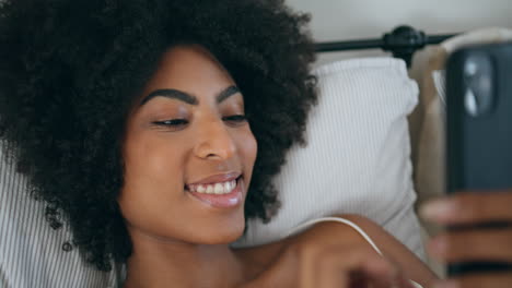 Lächelnde-Frau,-Die-Im-Bettporträt-In-Die-Kamera-Blickt.-Afrikanisches-Mädchen-Tippt-Mobiltelefon