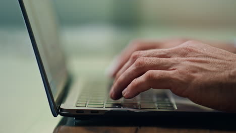 Man-hands-texting-laptop-keyboard-at-office-closeup.-Unknown-businessman-working