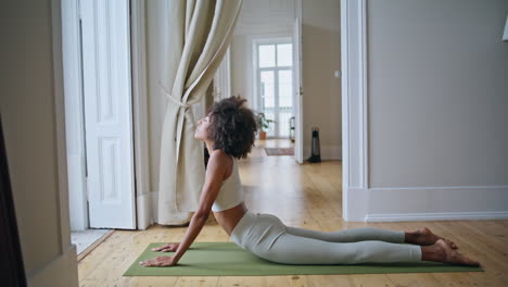 Strong-woman-cobra-pose-practicing-home.-African-girl-stretching-body-yoga-asana
