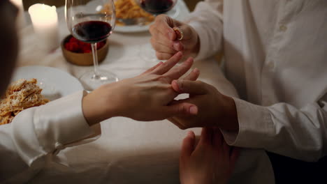Man-hands-wearing-engagement-ring-romantic-dinner-close-up.-Two-lovers-proposal