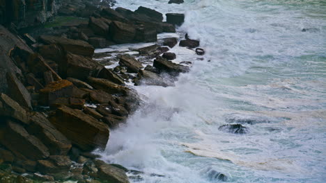 Foamy-ocean-washing-rocks-coastline-on-stormy-day.-Powerful-waves-breaking-beach