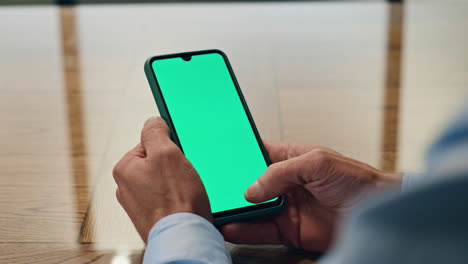 Man-hand-scrolling-greenscreen-smartphone-indoor-closeup.-Manager-holding-phone