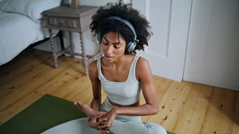 Relaxed-woman-stretching-legs-bedroom.-African-lady-listening-music-meditating