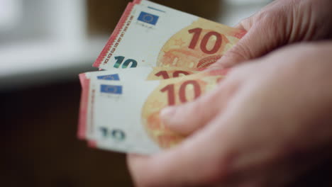 Hands-counting-small-savings-indoors-closeup.-Unknown-man-calculating-euro-bills