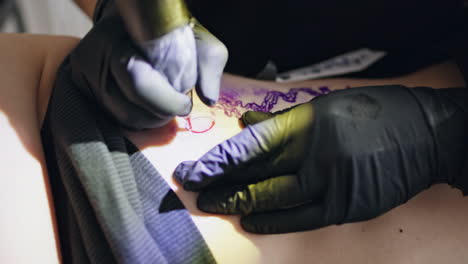 Master-hands-making-tattoo-at-salon-close-up.-Unknown-tattooist-working-machine