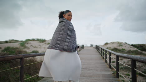 Attractive-woman-walking-wooden-path-on-cloudy-day.-Calm-serene-african-american