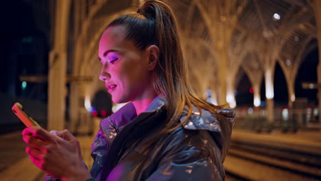 Girl-looking-smartphone-screen-stand-night-city-at-gothic-architecture-closeup
