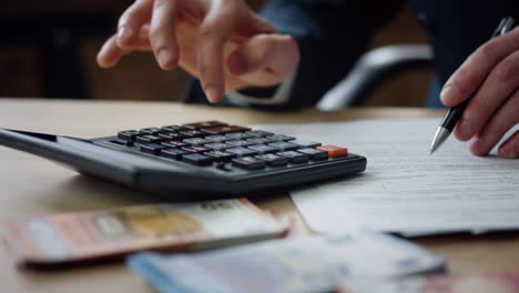 Man-hands-pressing-calculator-buttons-counting-tax-financial-bills-close-up.